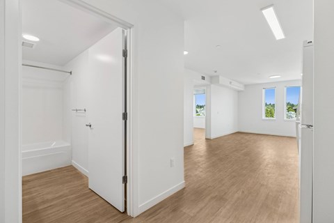 A white door is open to a room with wood flooring.