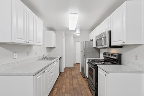 A kitchen with white cabinets and black appliances.