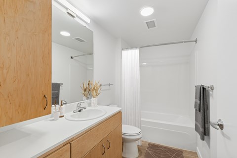 A white bathroom with a wooden cabinet and a white toilet.