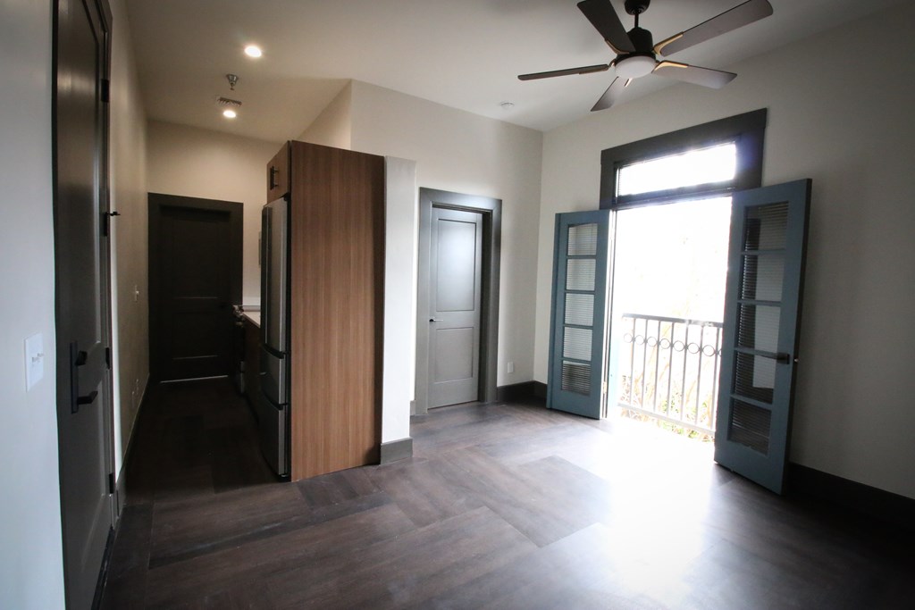 A room with a ceiling fan and sliding glass doors.