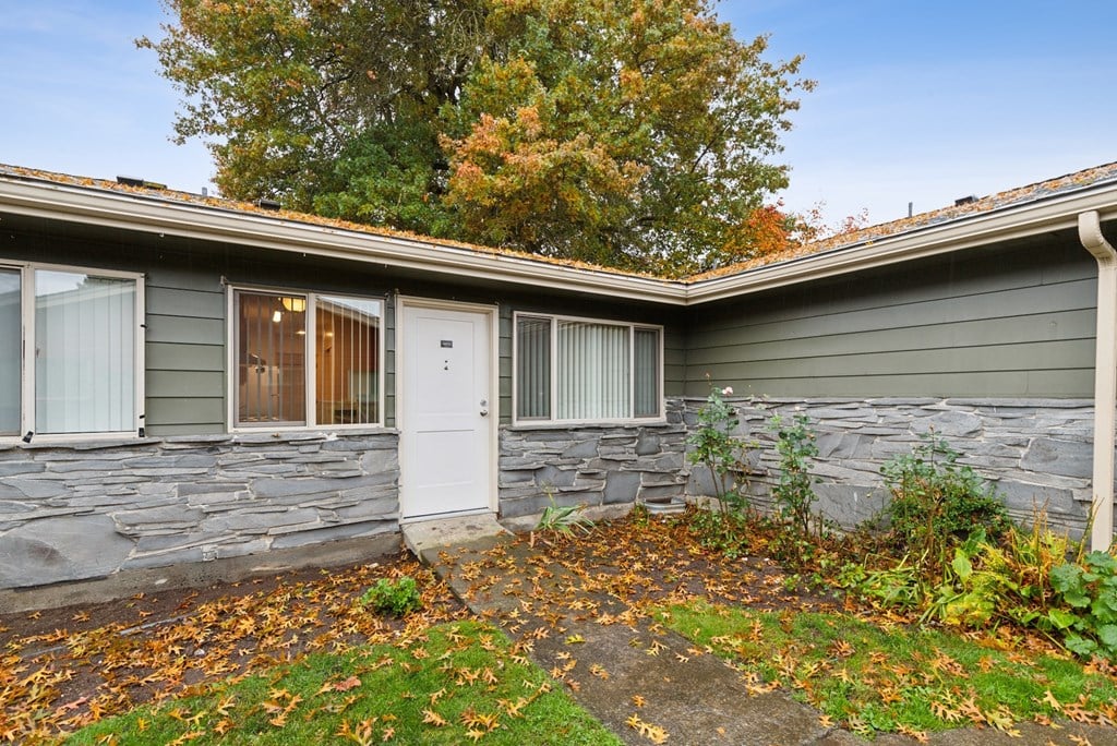 A house with a grey stone wall and a white door.