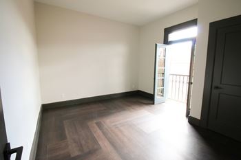 A room with wooden floors and a door leading to a balcony.