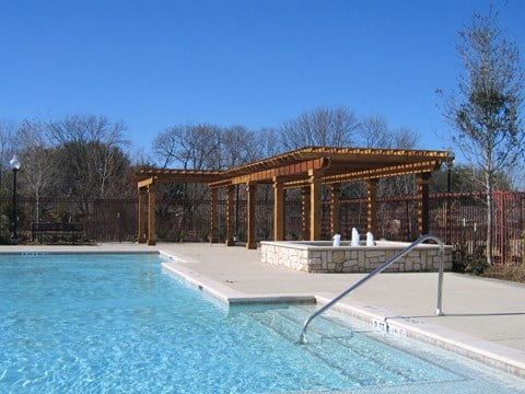 a pool with a wooden pavilion next to a swimming pool