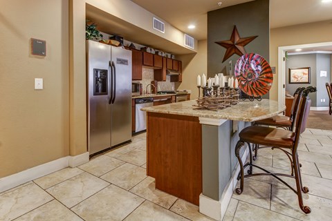 A kitchen area with a fridge and a bar space.