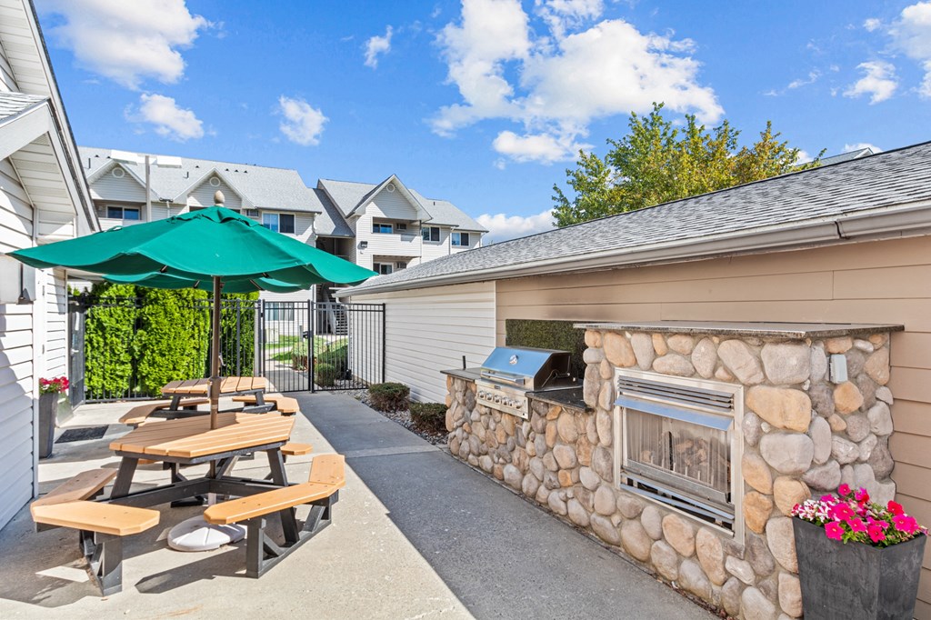 an outdoor patio with picnic tables and a stone fireplace