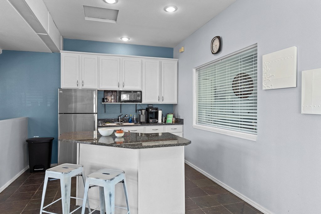 a kitchen with a bar and stools in front of a window and a counter