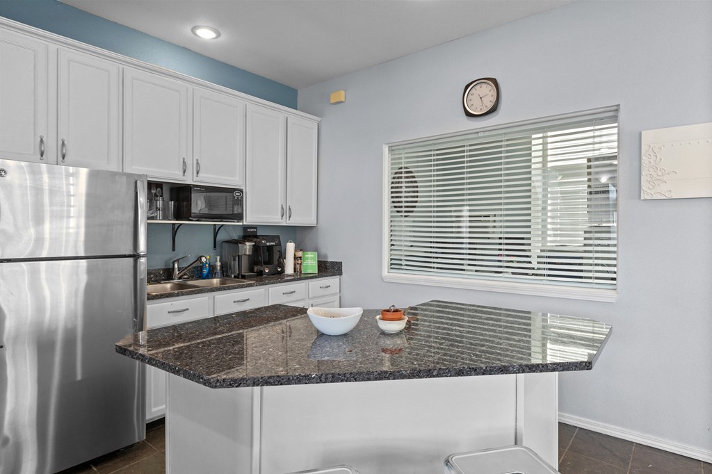 a kitchen with a granite counter top and a stainless steel refrigerator