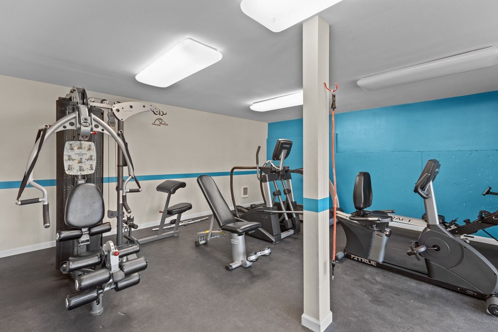 a gym with treadmills and other exercise equipment and a blue wall