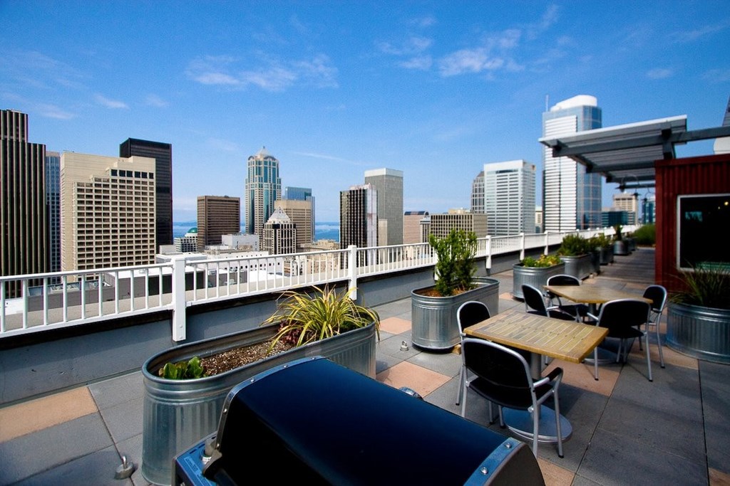 A rooftop patio with a table and chairs overlooking a city skyline.