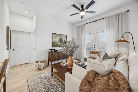 A living room with a brown and white couch, a coffee table, and a painting on the wall.