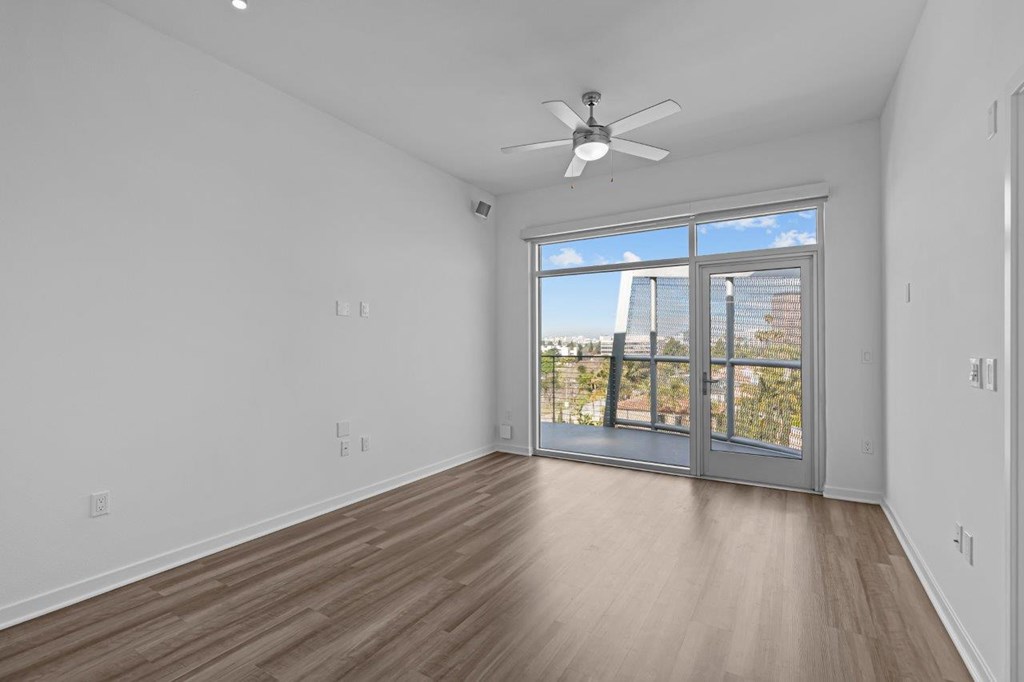 A room with a ceiling fan and sliding glass doors.