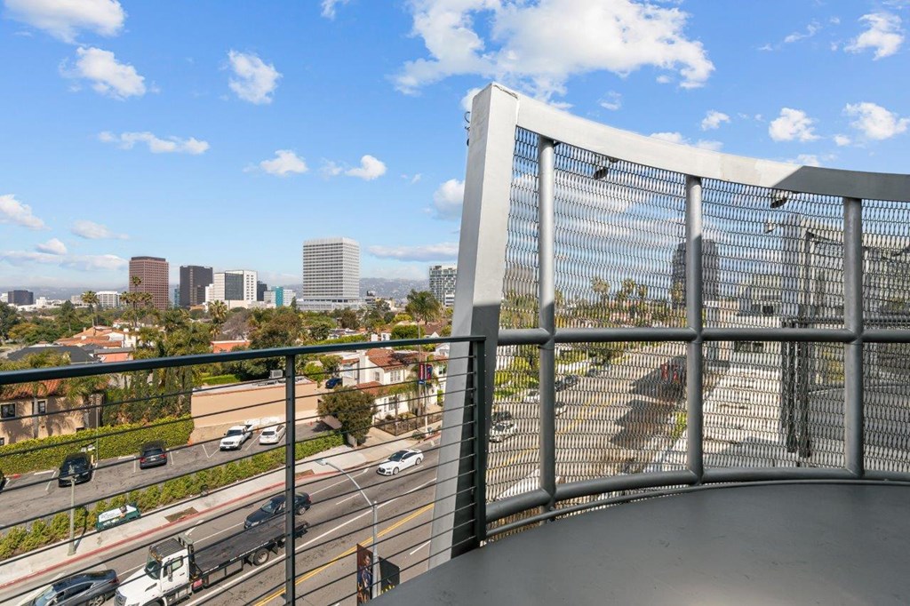 A cityscape viewed from a balcony with a metal railing.