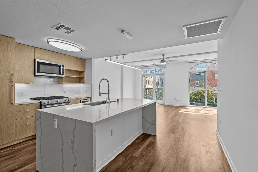 A modern kitchen with a white countertop and wooden cabinets.