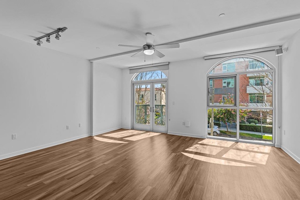 A room with a ceiling fan and a large window with a view of a building outside.