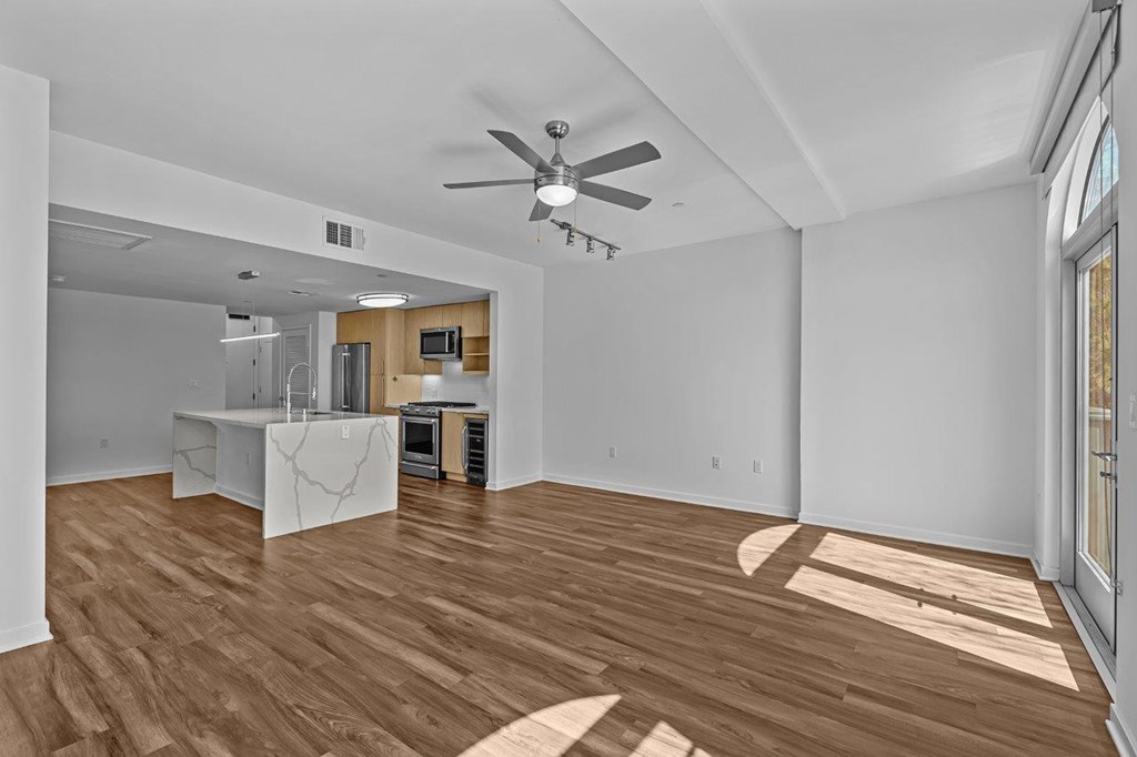 A room with a ceiling fan and wooden flooring.