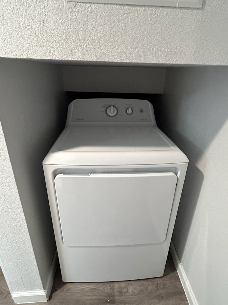 A white washing machine in a small, white-walled laundry room.