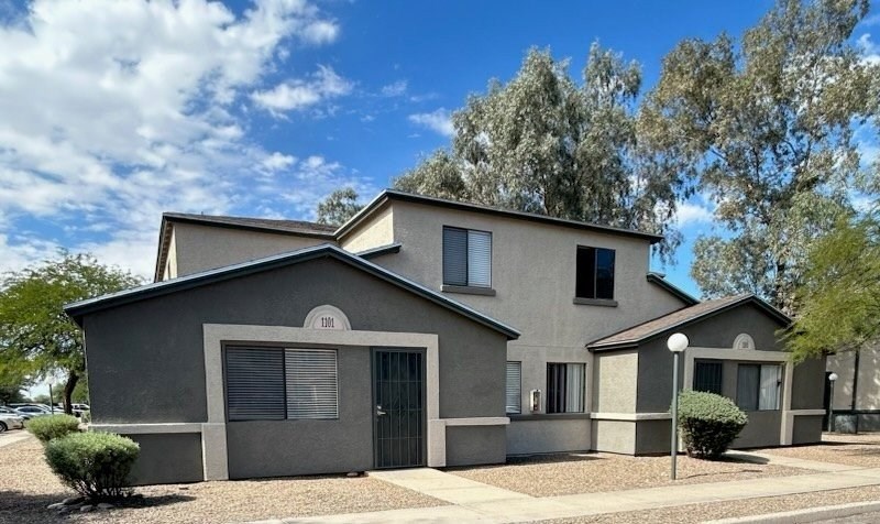 A modern house with a grey exterior and a black gate.