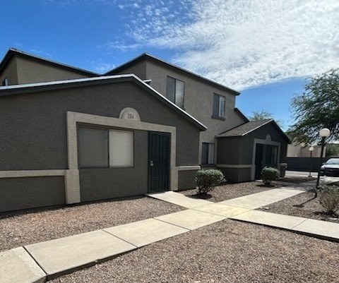 A modern house with a gravel driveway and a small tree.