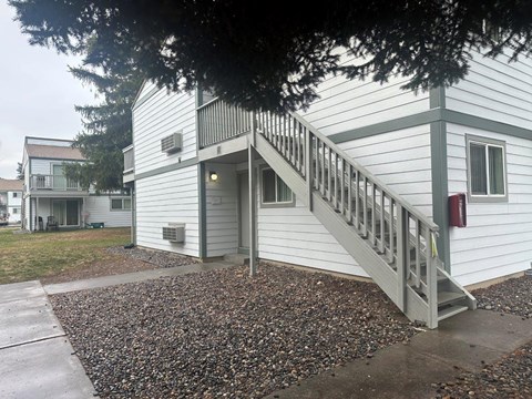 A white house with a grey staircase leading to the front door.