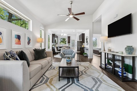 A living room with a beige couch, a coffee table, and a ceiling fan.