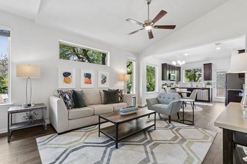 A living room with a white couch, a coffee table, and a ceiling fan.
