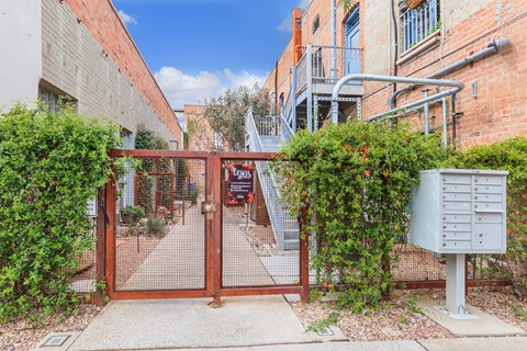 A gate with a mailbox on the side of a brick building.