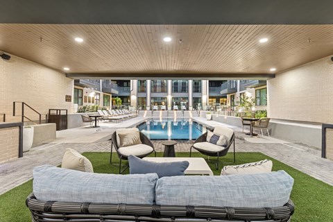 A patio with a pool and lounge chairs.