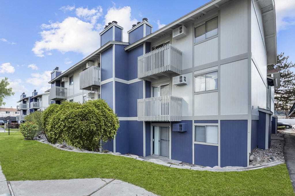 a blue and white apartment building with a sidewalk and grass