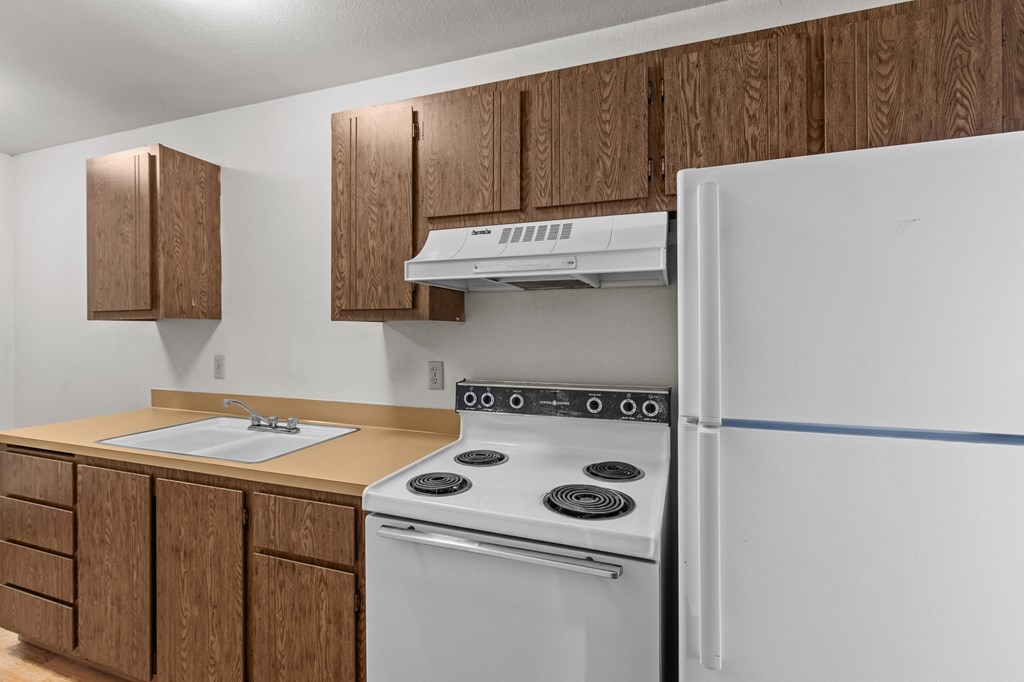 Creekside Apartments a kitchen with white appliances and wooden cabinets and a refrigerator