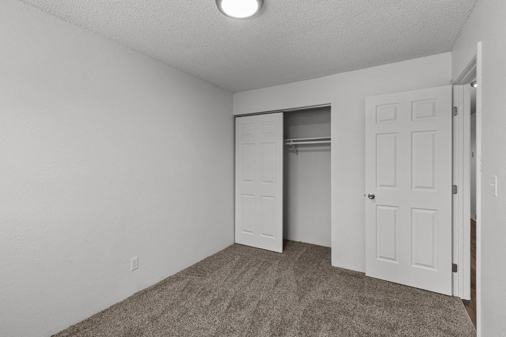 Creekside Apartments  an empty bedroom with a closet and an open door