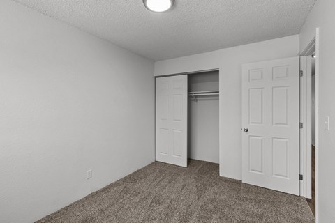 Creekside Apartments  an empty bedroom with a closet and an open door