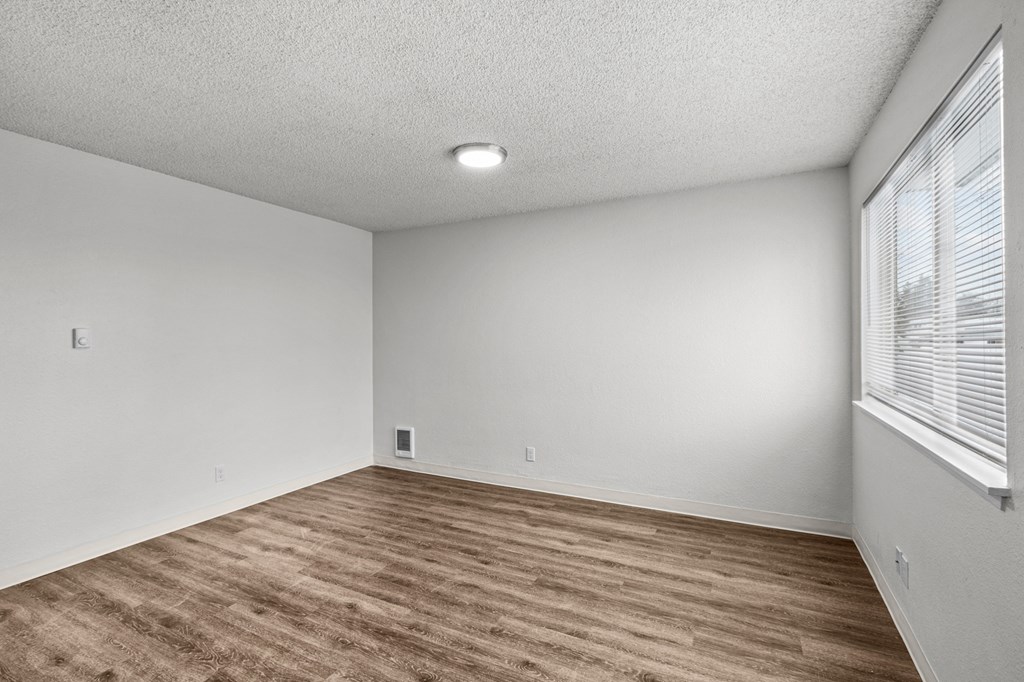 Creekside Apartments the spacious living room with a large window and wood flooring