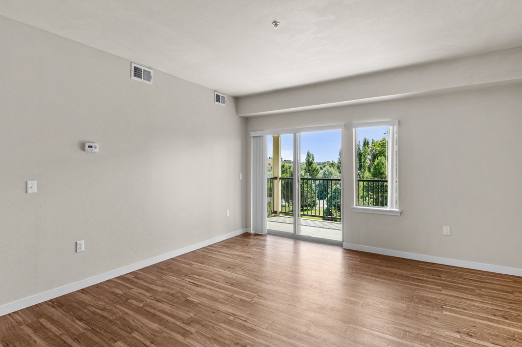 a bedroom with hardwood floors and a sliding glass door leading to a balcony