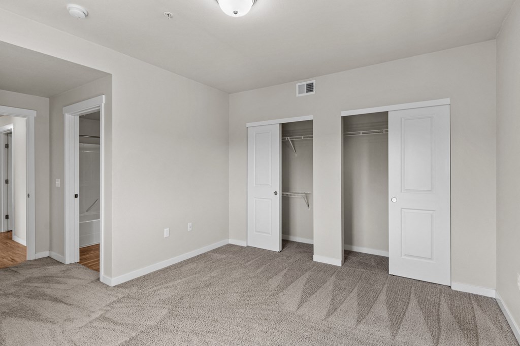 a bedroom with three closets and a carpeted floor