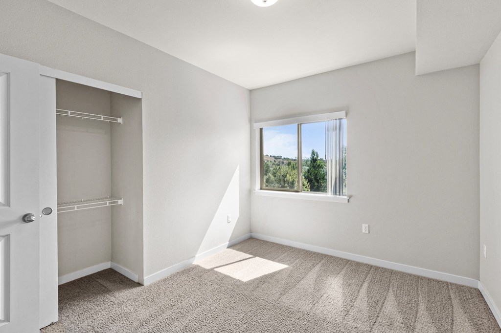 an empty bedroom with a large window and a closet
