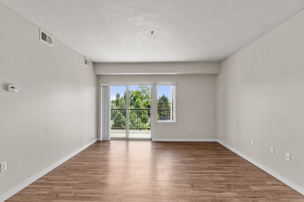 a bedroom with hardwood flooring and a sliding glass door leading to a balcony