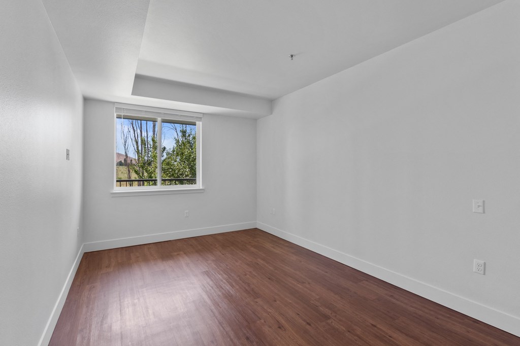 a bedroom with hardwood floors and a large window