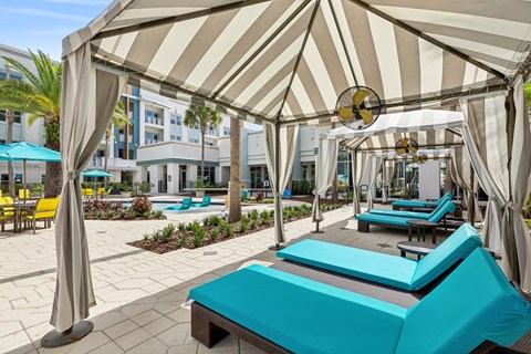 A sunny day at the pool with a striped umbrella providing shade.