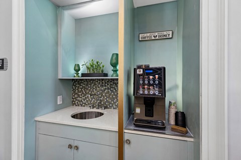A small counter with a sink and a coffee machine.