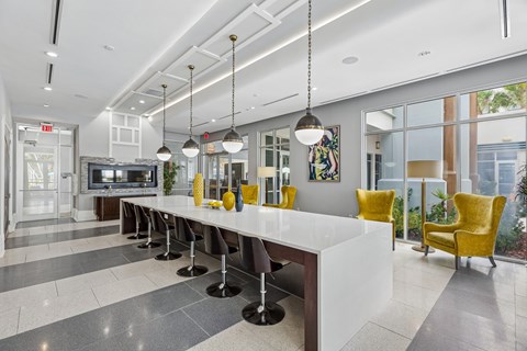 A long white table with yellow chairs and a fireplace in the background.