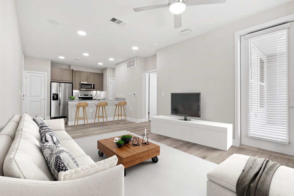 A modern living room with a white sofa, a wooden coffee table, and a television.