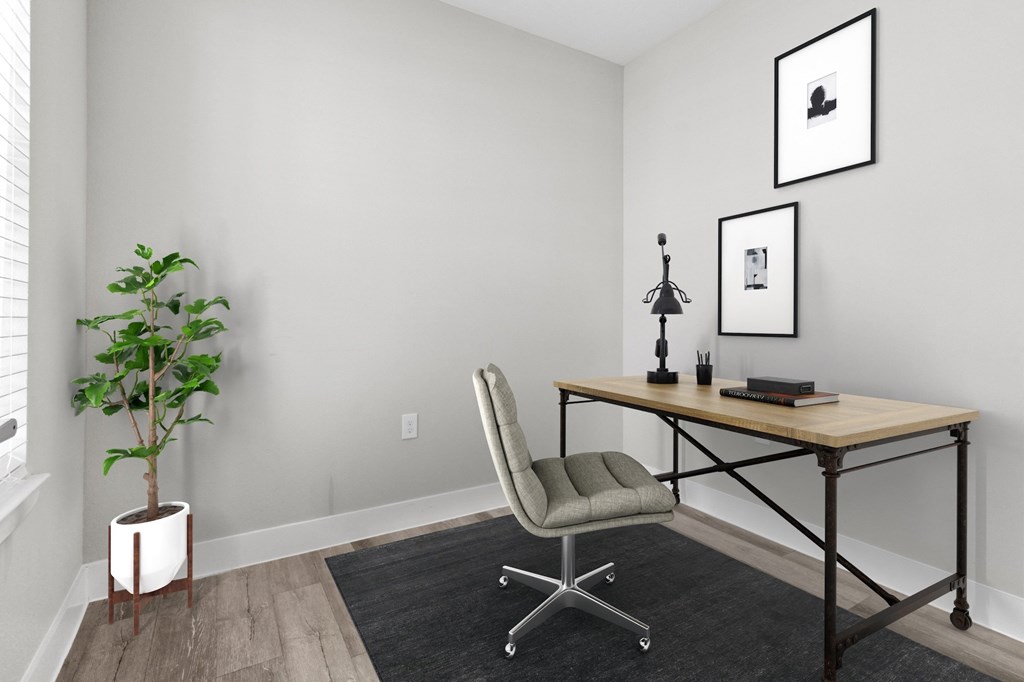 A room with a desk, chair, and plant.