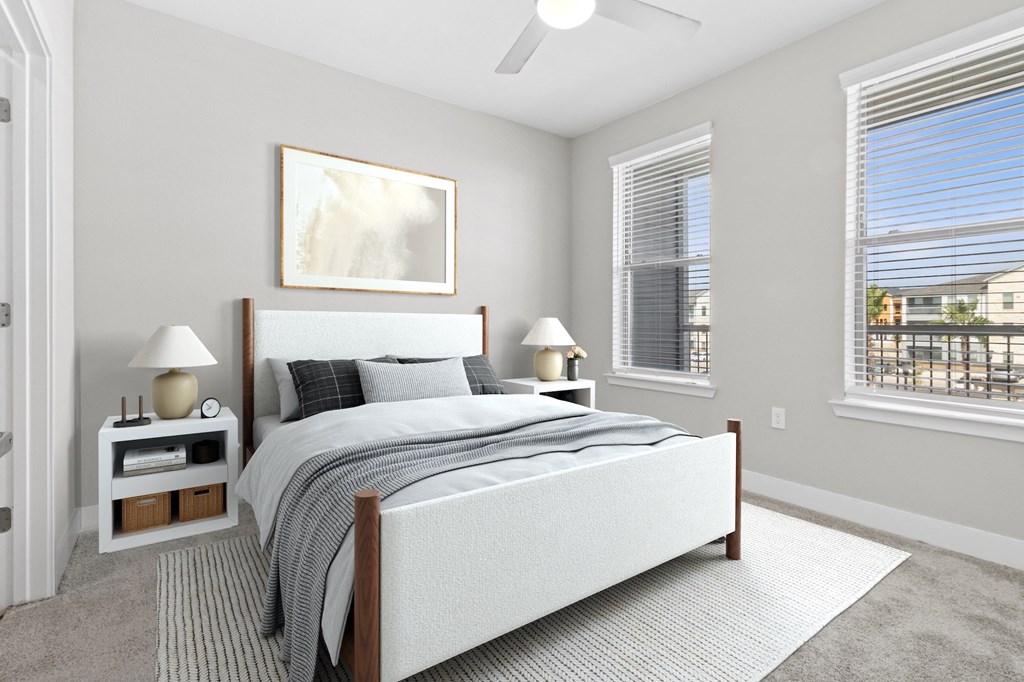 A bedroom with a large bed, a ceiling fan, and a window with blinds.