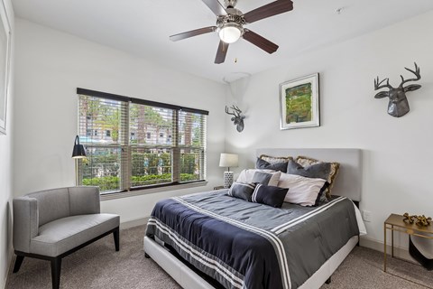 A bedroom with a bed, a chair, and a ceiling fan.