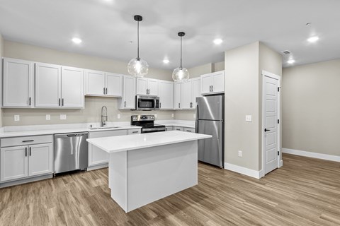 A kitchen with white cabinets and a white island.
