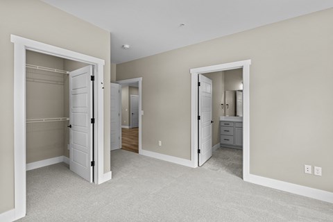 a bedroom with two closets and a bathroom in the background