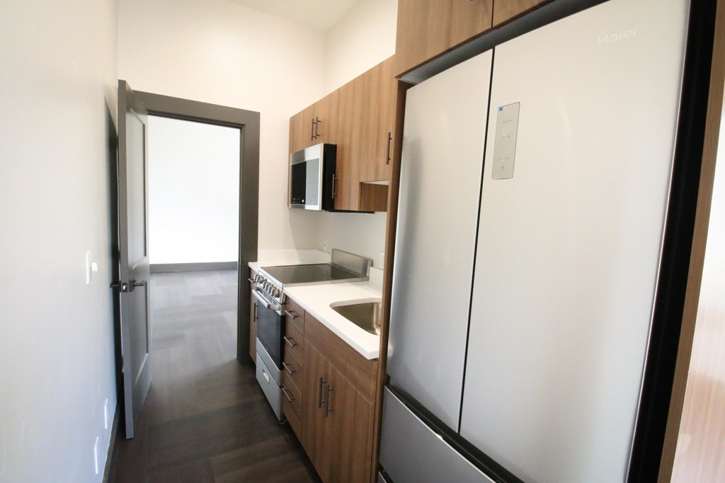 A kitchen with a white fridge, microwave, and oven.