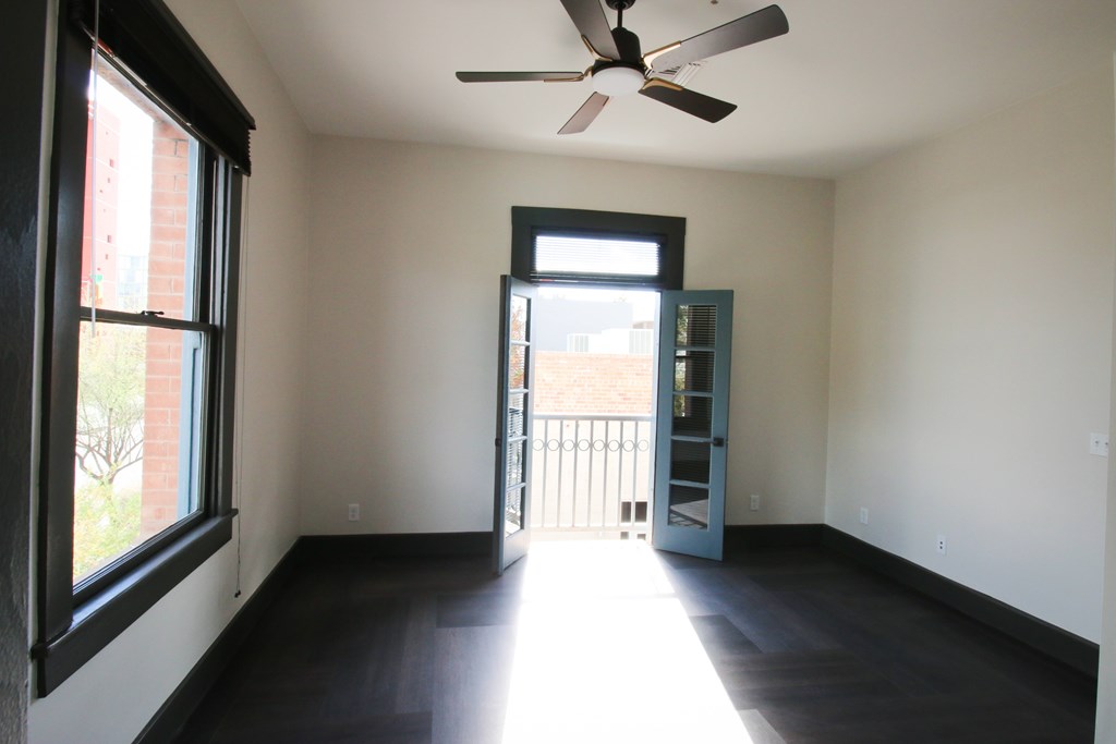 A room with a ceiling fan and a door leading to a balcony.