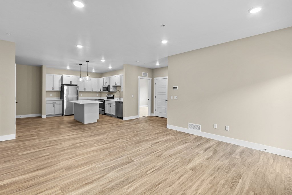 a spacious living room with a kitchen in the background