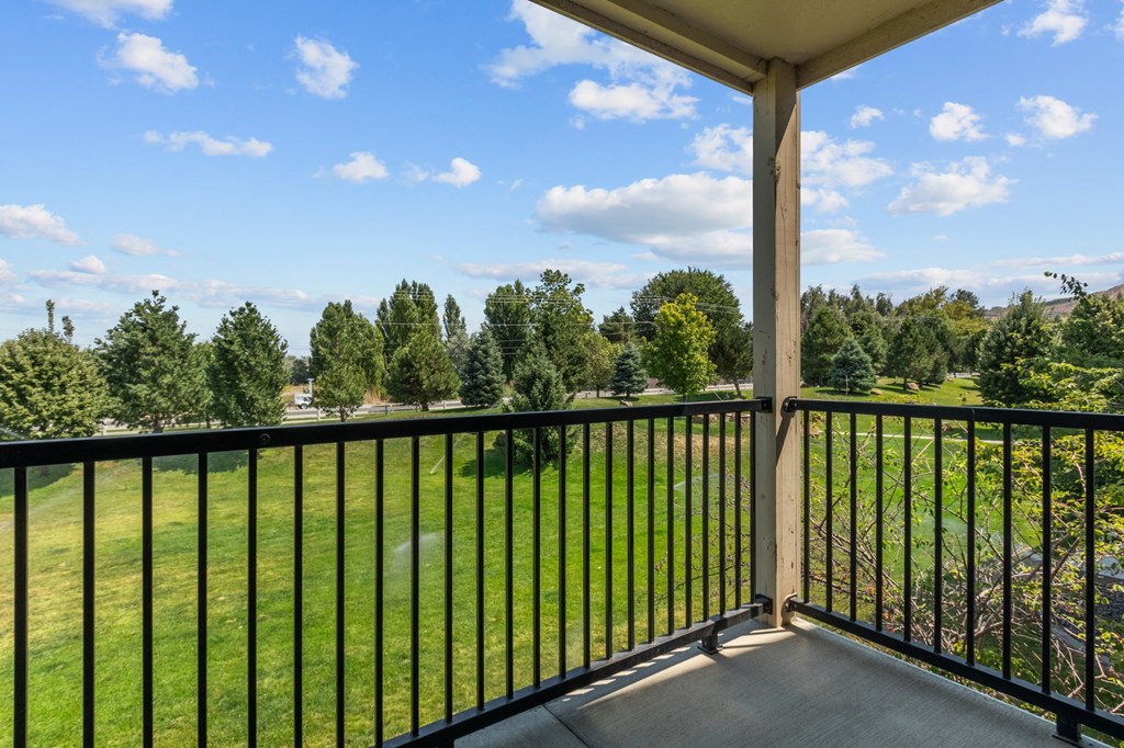 a balcony with a view of a grassy field and trees